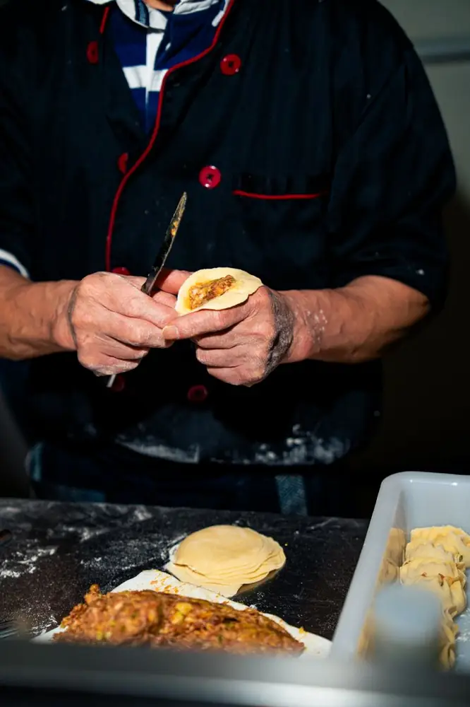 Il cuoco chiude a mano un raviolo con il ripieno