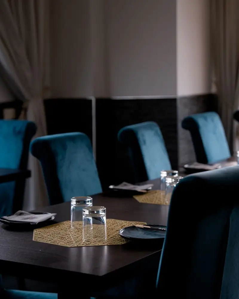 La sala di Ukiyo con sedie in velluto blu e tavoli in legno scuro apparecchiati