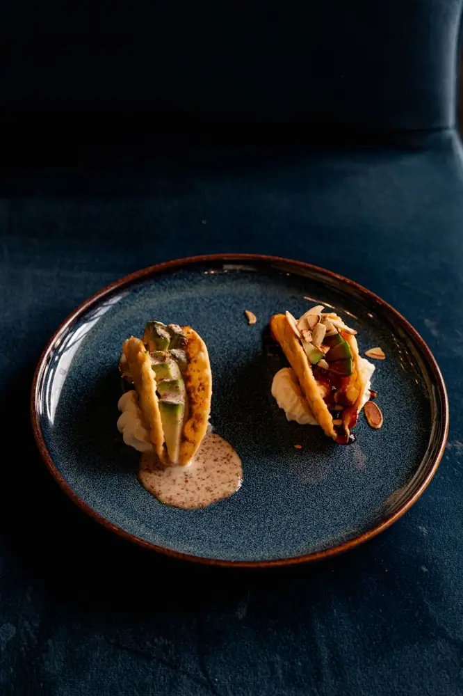 Tacos croccanti con avocado, mandorle e salsa su piatto blu