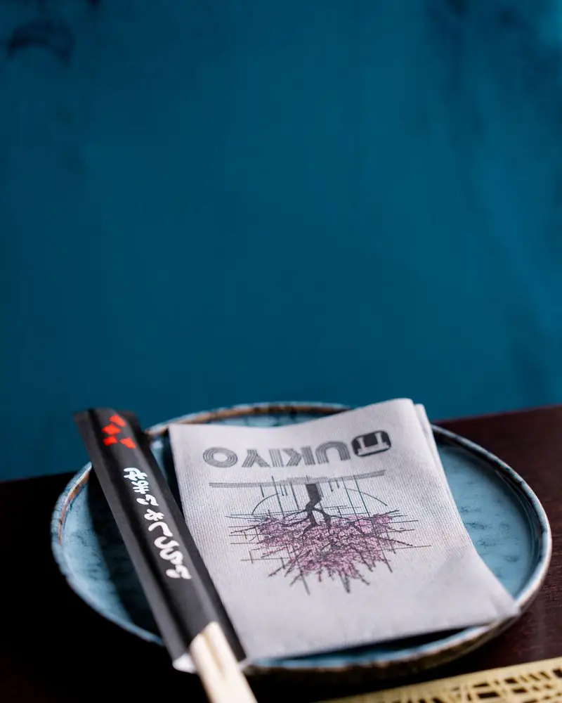 Tovagliolo con il logo Ukiyo e bacchette su un piatto in ceramica blu